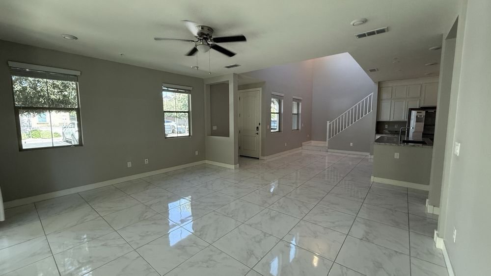 An empty living room with gleaming marble-look tile floors after a move-out clean