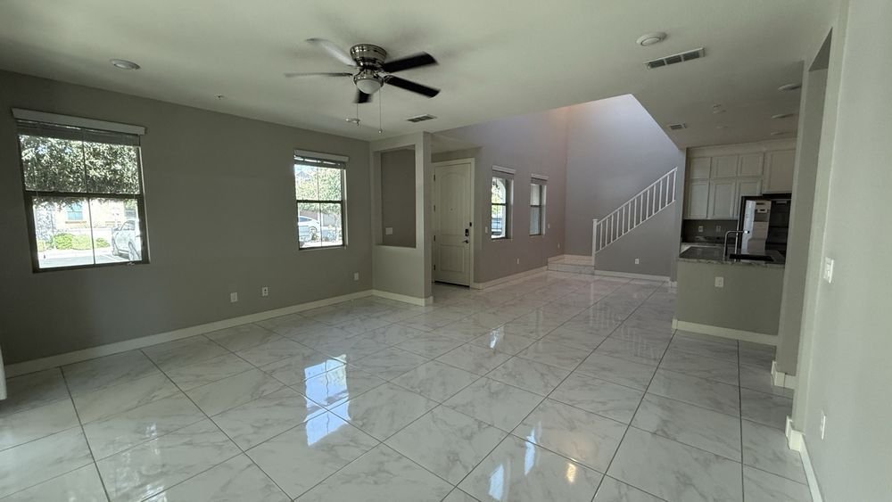 An empty living room and entryway with clean tile floors and bright windows