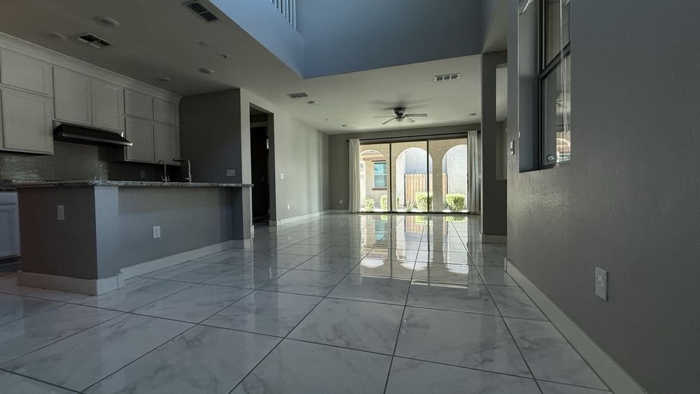 An empty open-plan kitchen and living area with polished tile floors